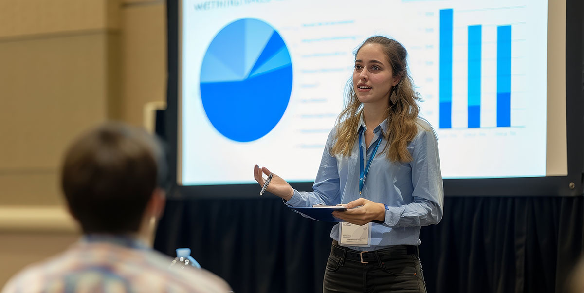 Student giving presentation in front of screen with chart